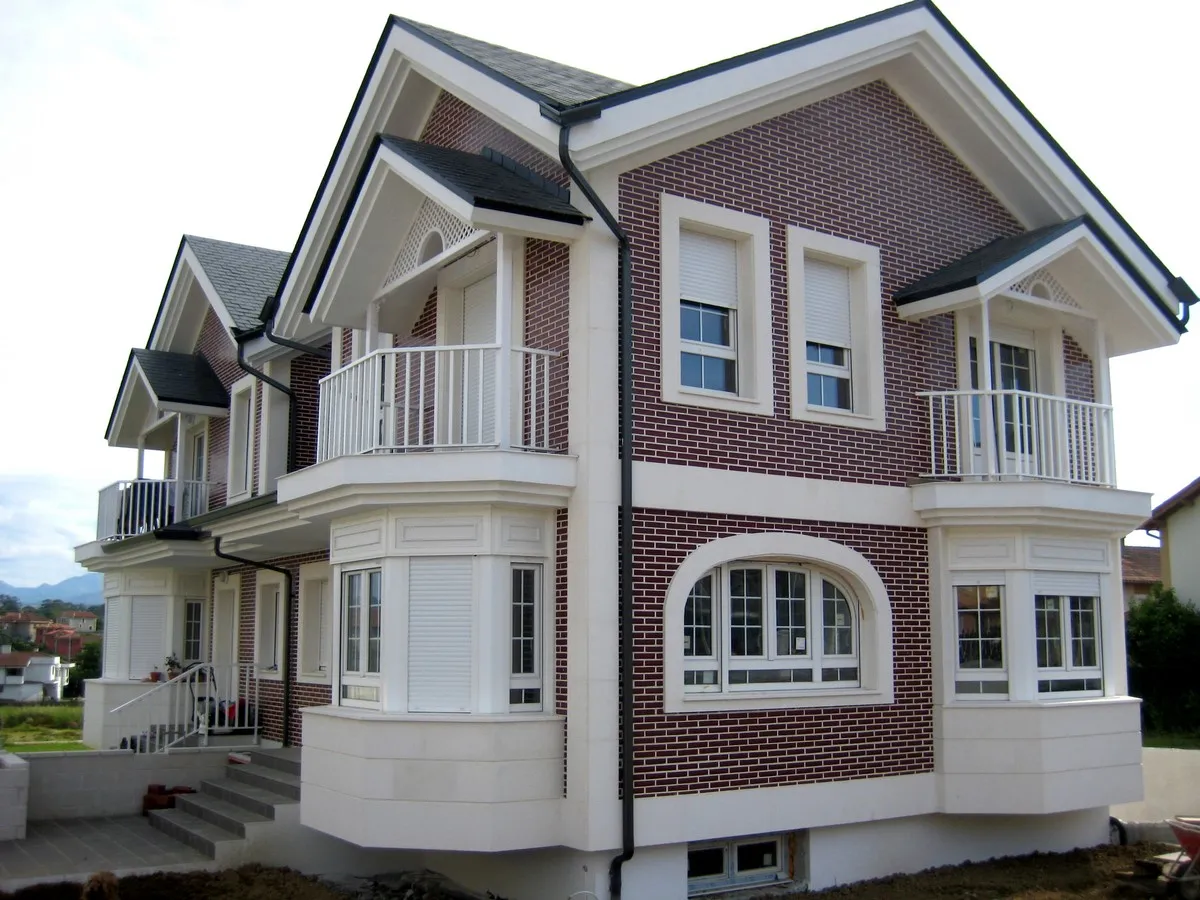 Chalet de tres plantas con fachada de ladrillo y balcones blancos construido para Promociones Proarla S.L.
