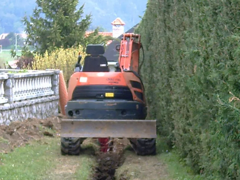 Minipala Kubota trabajando junto a un seto